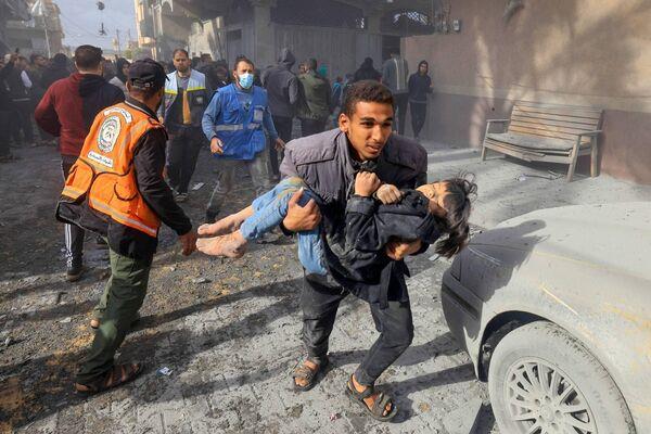 A man carries a child injured in an Israeli strike on Rafah in the southern Gaza Strip on November 20, 2023. Picture: MAHMUD HAMS/AFP via Getty Images