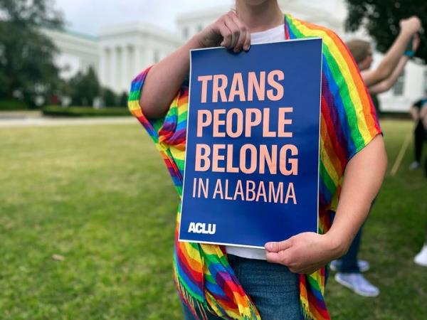A person holds up a sign reading,