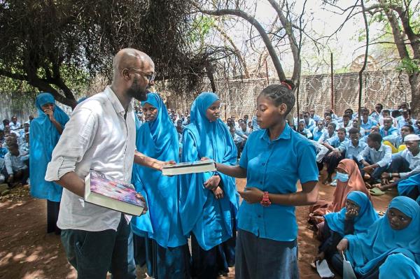 Mire (left) distributing books to refugee students in Kenya's Dadaab refugee camp. Photo: AFP